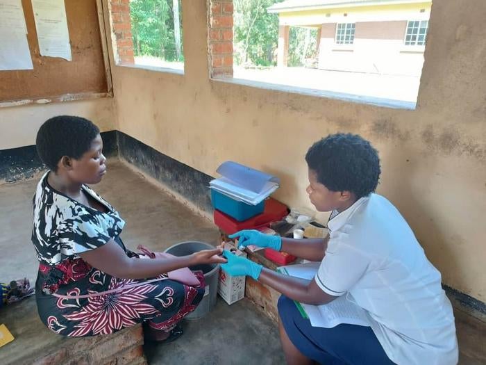 A study nurse screens a pregnant participant for anaemia by collecting a blood sample for haemoglobin.
